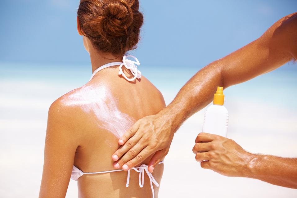 Portrait of man applying sun block lotion on woman's back
