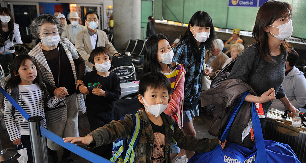 An Asian family wears face masks to protect themselves from the risk of contracting swine flu, as they arrive at Los Angeles International Airport on April 29, 2009. A Mexican toddler also became the first person to die in the United States of H1N1 swine flu, which is spreading throughout the United States with new cases confirmed in four more states and the total number of known victims jumping from 65 to 91, officials said.            AFP PHOTO/Mark RALSTON (Photo credit should read MARK RALSTON/AFP via Getty Images)