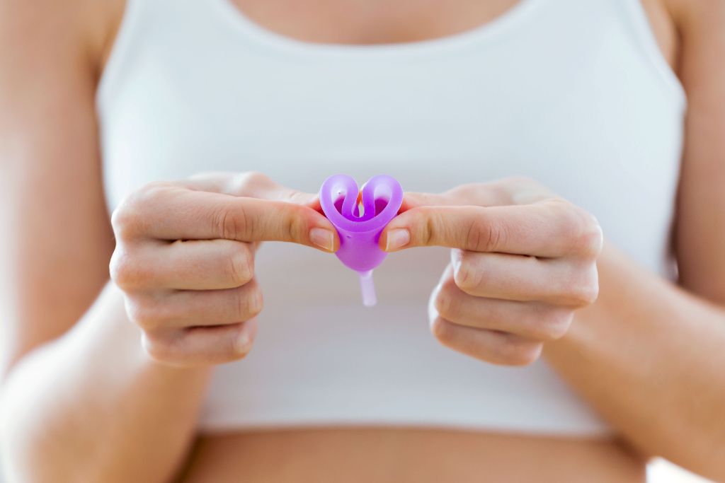 Young woman hands folding a menstrual cup.