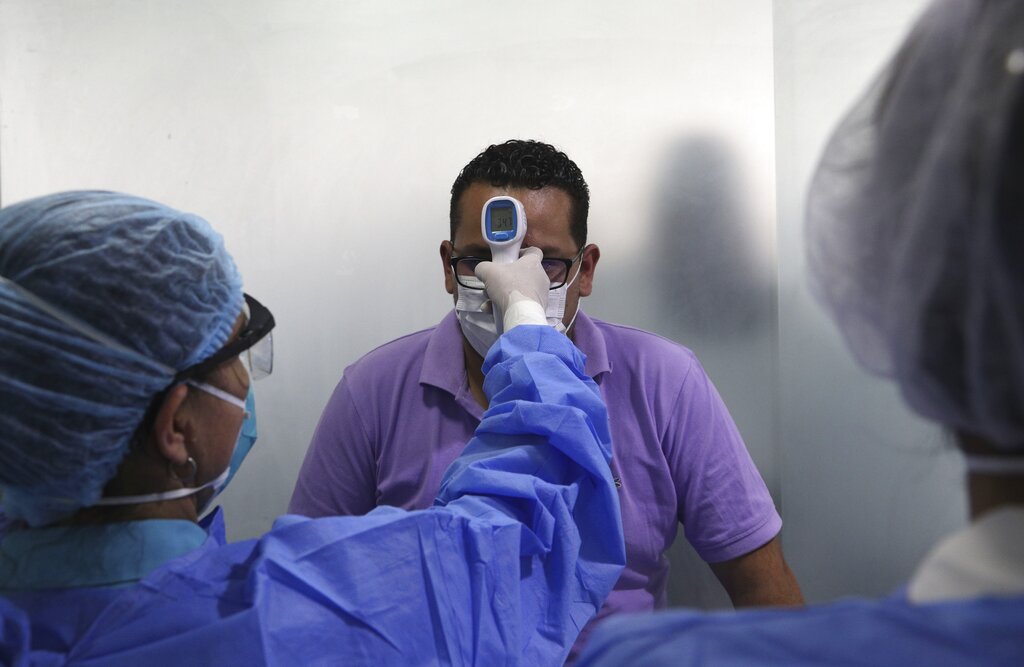 Personal sanitario toma la temperatura a un hombre en un pequeño centro médico en Lima, el miércoles 11 de marzo de 2020, como medida preventiva contra la propagación del nuevo coronavirus. La mayoría de la gente se recupera de la enfermedad COVID-19 causada por ese virus. (AP Foto/Martín Mejía)