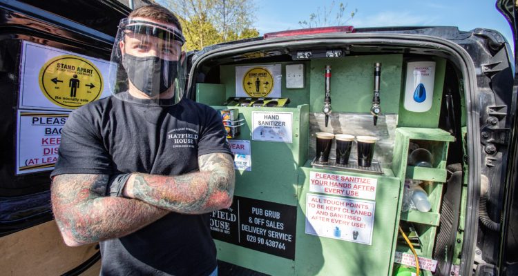 Harry McKeaveney from The Hatfield House bar, poses wearing PPE (personal protective equipment) of a face mask and gloves, as he stands with the pub's converted delivery van in which they deliver a 'freshly poured' pint of Guinness to customers' front doors, in Belfast, Northern Ireland, on April 16, 2020. - When the British Government closed all non-essential services, including pubs and bars, as a result of the novel coronavirus pandemic, Belfast's Hatfield House bar came up with an innovate idea to take online orders and deliver pints of freshly poured Guinness, from the back of a van. (Photo by PAUL FAITH / AFP)